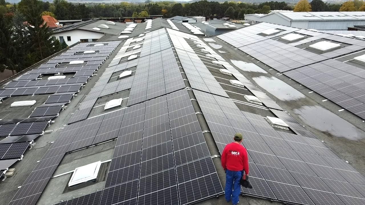 Großes Industriedach mit PV-Modulen und Monteur